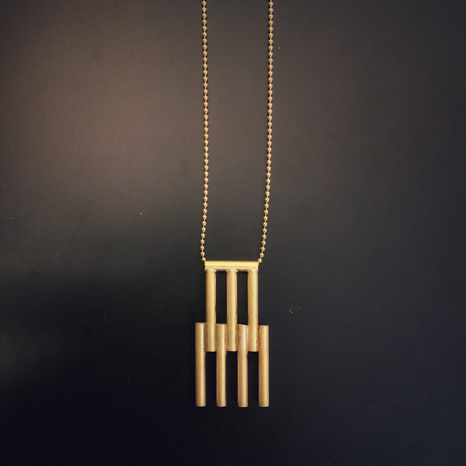 Colgante de oro con flecos, sobre cadena larga